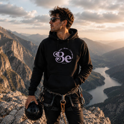 Man wearing The Avielle Be Bold Black Edition Joshua 1:9 hoodie during a mountain climbing adventure.