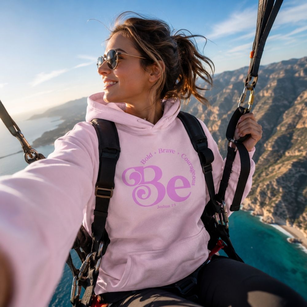 Woman paragliding while wearing the Be Bold Joshua 1:9 white Christian hoodie by The Avielle