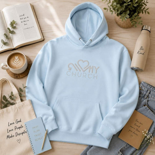 Woman wearing the Love My Church embroidered sky blue premium hoodie in a modern church by The Avielle