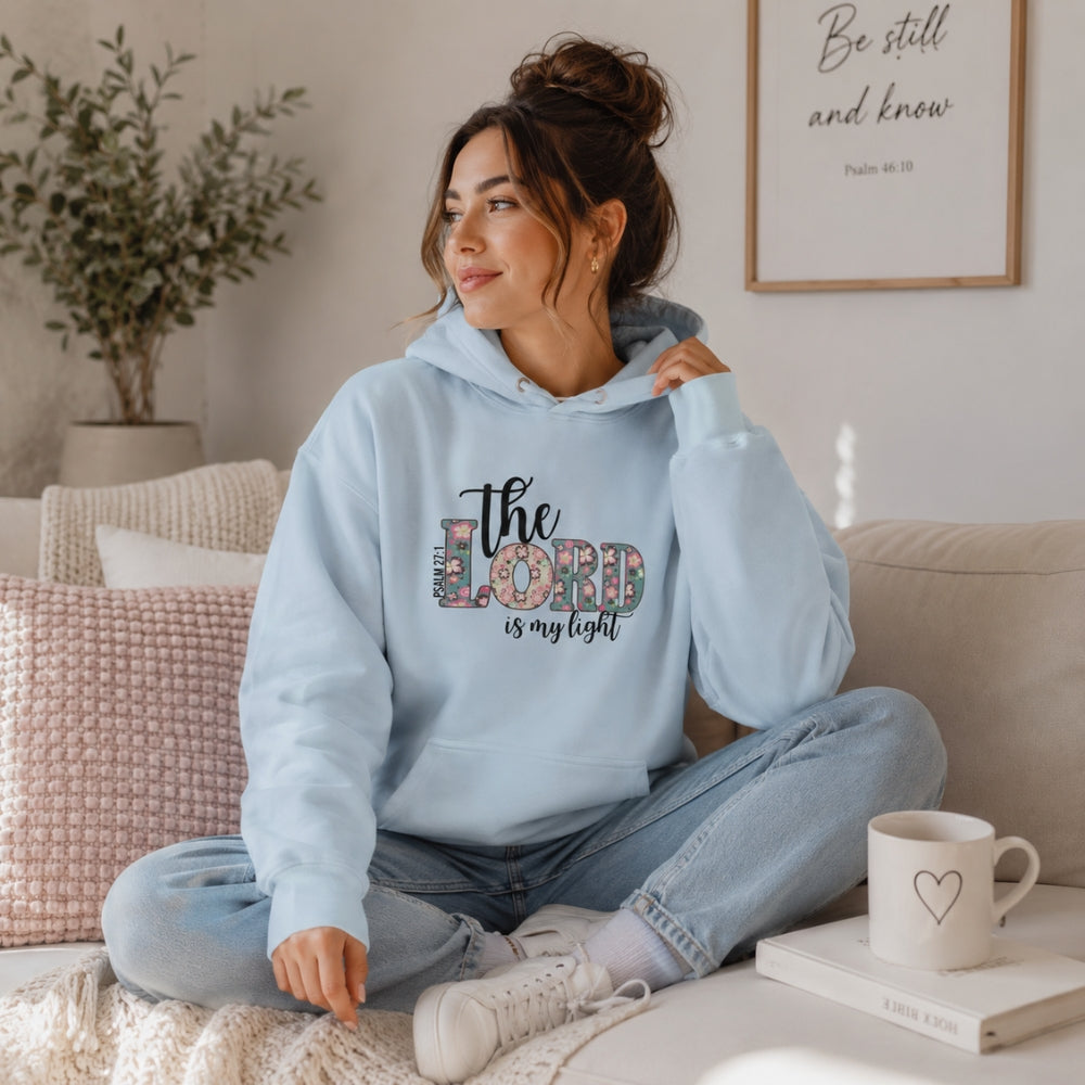 Woman wearing The Lord Is My Light Psalm 27:1 Christian hoodie in sky blue in a cozy lifestyle setting.